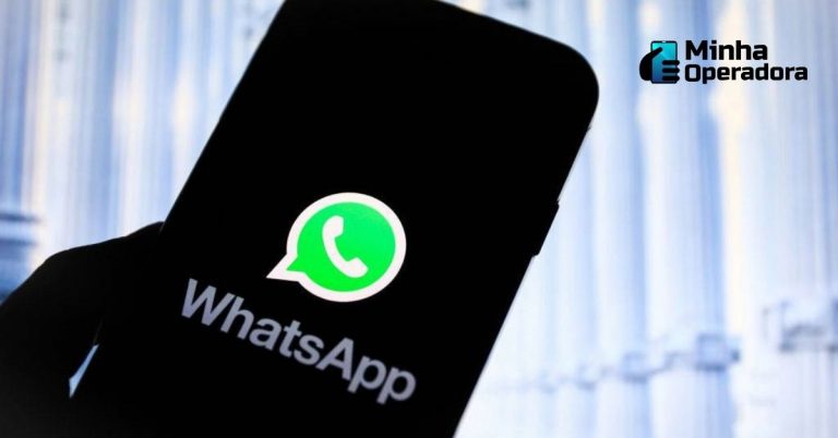 Pessoa segurando o celular contraluz, destacando o logotipo do WhatsApp.