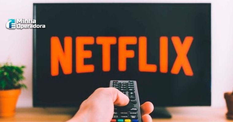 Mão aponta o controle para a TV com o símbolo da Netflix.