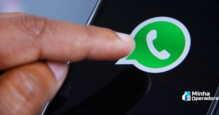 A mão de um usuário tecla o símbolo do WhatsApp na tela do celular.