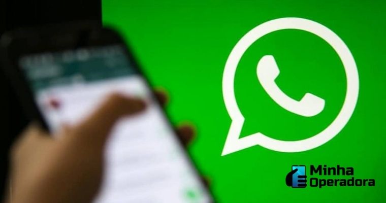 Em primeiro plano aparece um celular desfocado, com a logomarca do WhatsApp ao fundo.