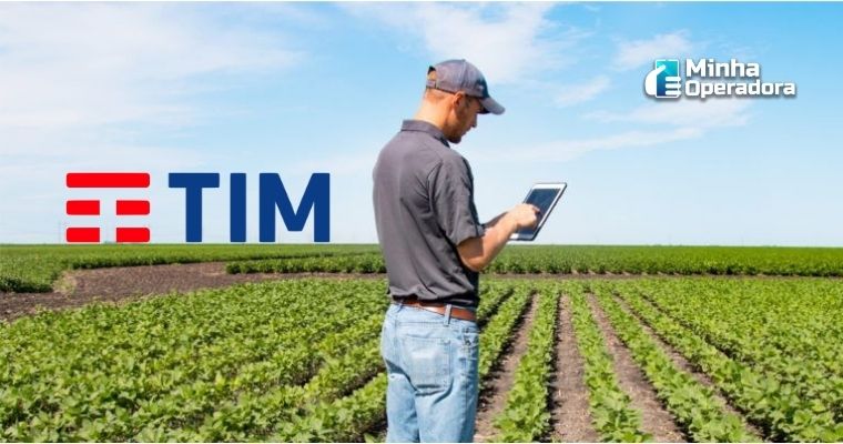 Homem utilizando o tablet no meio da plantação com o logotipo da TIM no horizonte.