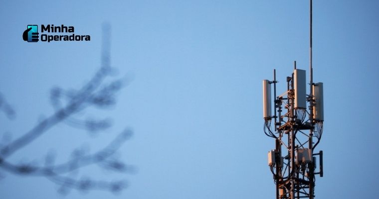 Fotografia com uma antena de celular e um galho de árvore desfocado na frente.